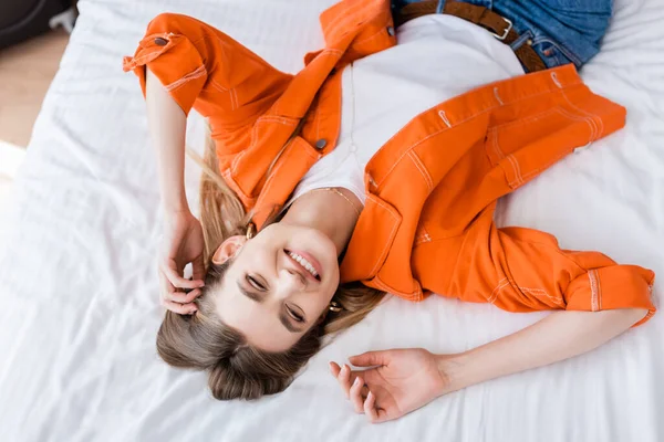 Top view of pleased young woman relaxing on bed in hotel room — Stock Photo