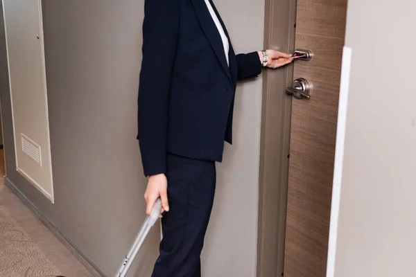 Cropped view of businesswoman in suit holding room card while unlocking door in hotel — Stock Photo