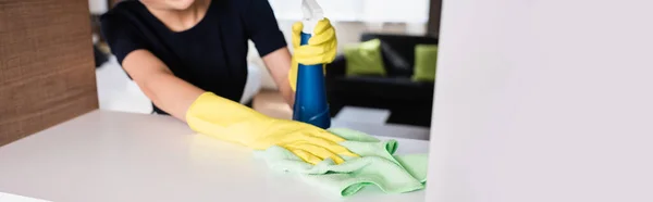 Colheita horizontal de empregada doméstica em luvas de borracha segurando garrafa de spray e pano durante a limpeza prateleira no quarto do hotel — Fotografia de Stock