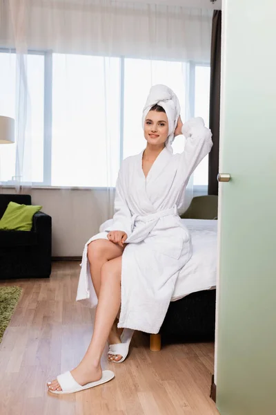 Frau in weißem Handtuch und Bademantel blickt in Hotelzimmer in die Kamera — Stockfoto