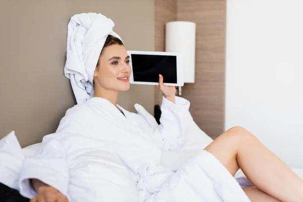 Mulher em toalha e roupão de banho branco segurando tablet digital com tela em branco no quarto do hotel — Fotografia de Stock