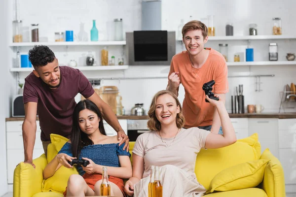 KYIV, UKRAINE - JULY 28, 2020: young man showing winner gesture near multicultural friends playing video game — Stock Photo