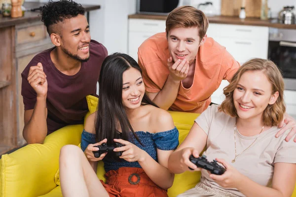 KYIV, UCRANIA - 28 de julio de 2020: amigos multiculturales emocionados jugando videojuegos durante la fiesta - foto de stock