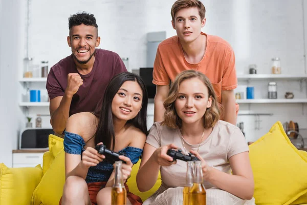 KYIV, UKRAINE - JULY 28, 2020: excited african american man showing winner gesture near multicultural friends playing video game — Stock Photo