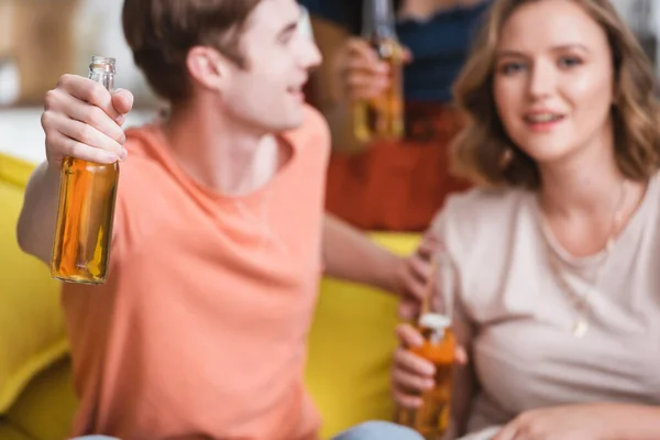 Selective focus of young man and woman holding bottles of beer during party — Stock Photo
