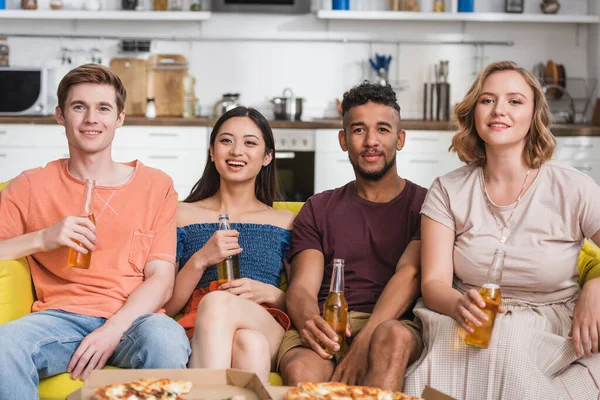 Multicultural friends with bottles of beer watching movie during party — Stock Photo