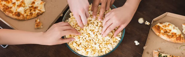 Teilansicht multikultureller Freunde, die während der Party Popcorn aus der Schüssel holen, horizontales Konzept — Stockfoto