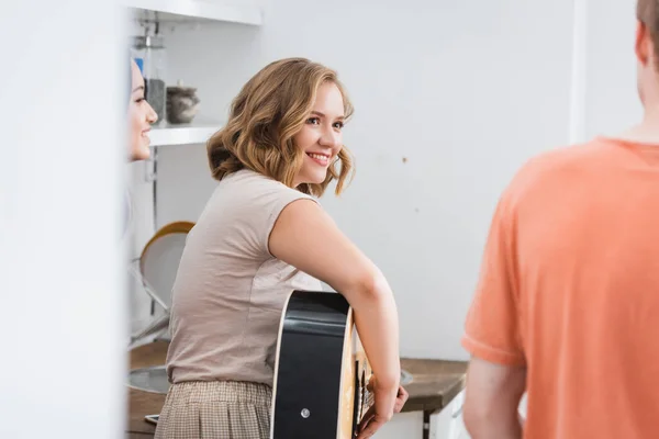 Focalizzazione selettiva di giovane donna che suona la chitarra vicino ad amici multiculturali — Foto stock