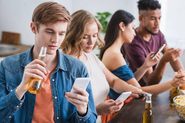 Selective focus of multicultural friends chatting on mobile phones during party — Stock Photo