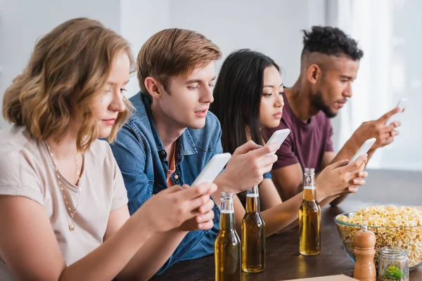 Selective focus of multicultural friends chatting on mobile phones during party — Stock Photo