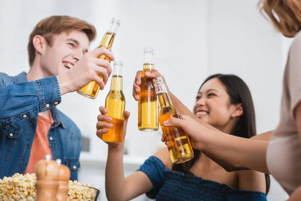 Foco seletivo de amigos multiétnicos batendo garrafas de cerveja durante a festa — Fotografia de Stock