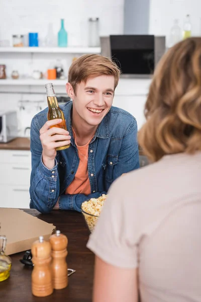 Избирательный фокус радостного молодого человека, держащего бутылку пива рядом с другом — стоковое фото