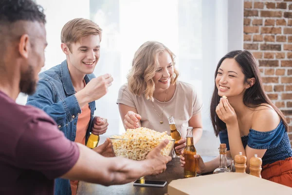 Amigos multiétnicos animado comer pipocas e falando durante a festa — Fotografia de Stock