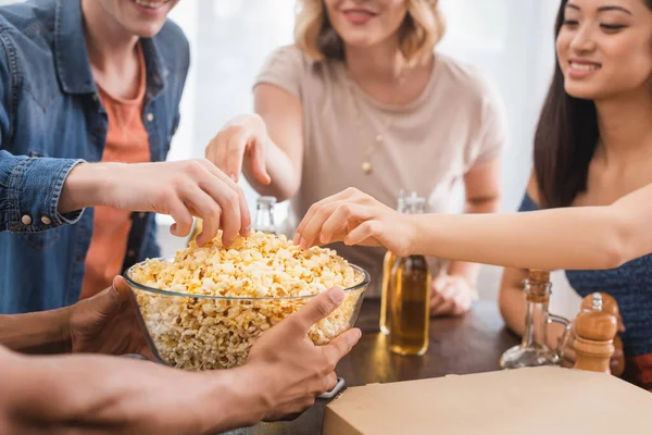 Enfoque selectivo de amigos multiétnicos que toman palomitas de maíz del tazón durante la fiesta - foto de stock