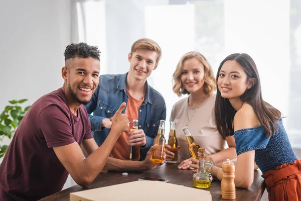 Aufgeregter afrikanisch-amerikanischer Mann zeigt bei Party Daumen hoch bei multikulturellen Freunden — Stockfoto