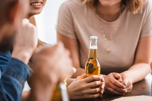 Обрезанный вид женщины, держащей бутылку пива рядом с мультикультурными друзьями — стоковое фото