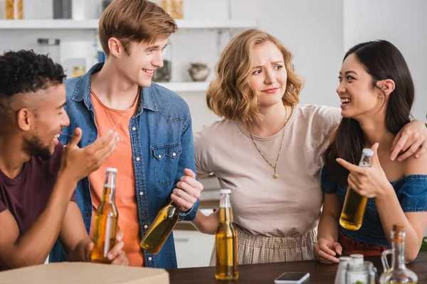 Excited multicultural friends with bottles of beer talking during party — Stock Photo