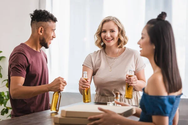 Foyer sélectif de la femme asiatique près de boîtes à pizza et amis multiculturels avec de la bière — Photo de stock