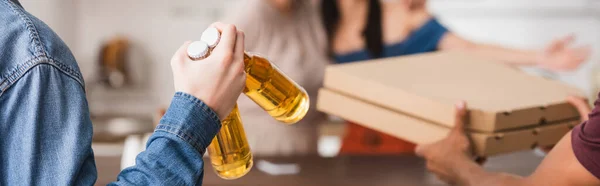 Cropped view of multicultural friends holding beer and pizza boxes, website header — Stock Photo