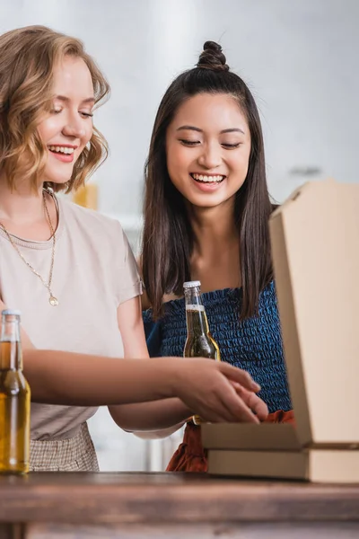 Amis multiculturels joyeux ouverture boîte à pizza pendant la fête — Photo de stock