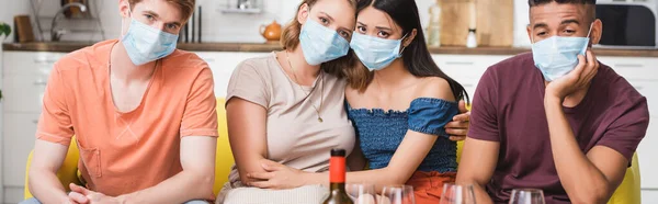 Coltura orizzontale di amici multiculturali tristi in maschere mediche che fanno festa durante la quarantena — Foto stock
