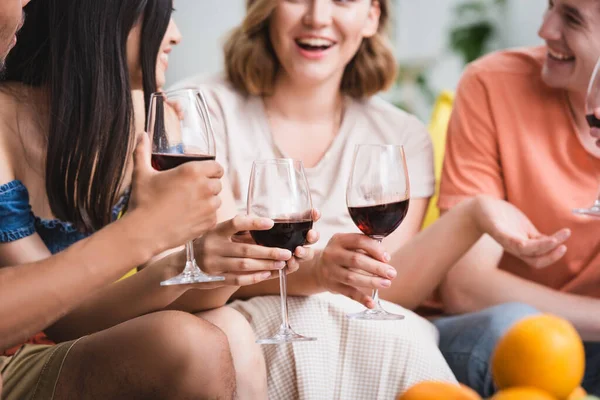 Селективное внимание мультикультурных друзей, держащих бокалы красного вина во время вечеринки — стоковое фото