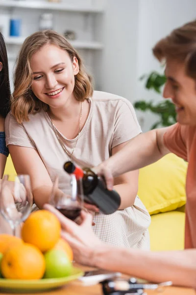 Selective focus of young man pouring red wine near friend — Stock Photo