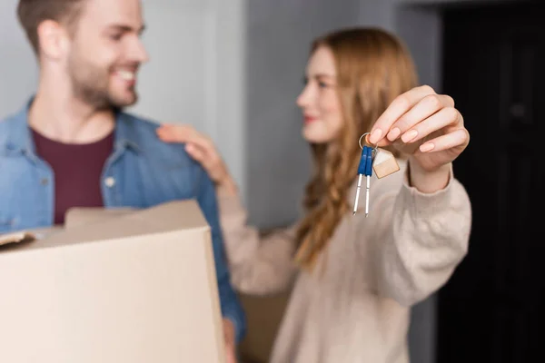Selective focus of woman holding keys near boyfriend with box — Stock Photo