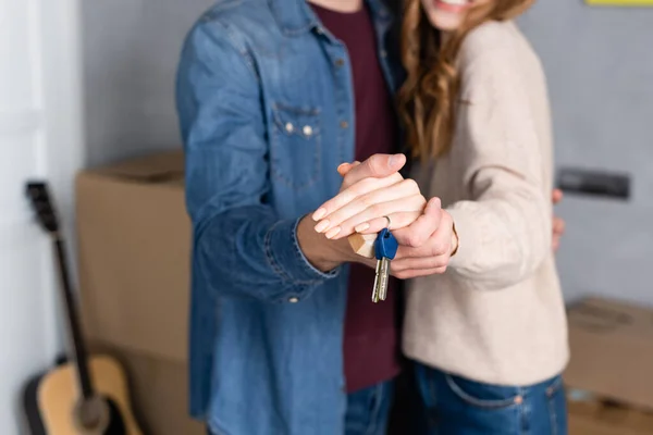 Vista ritagliata di uomo e donna che si tengono per mano e chiavi, concetto in movimento — Foto stock