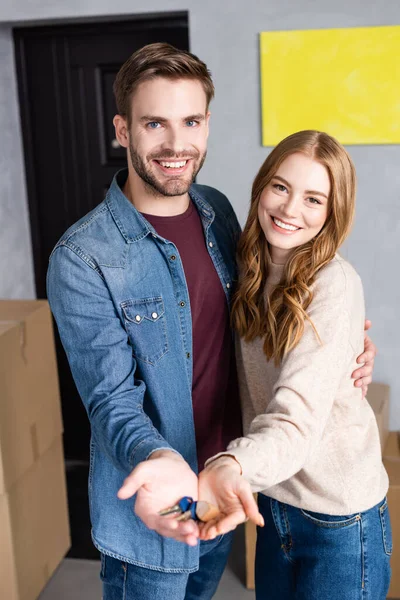 Hombre y mujer satisfechos sosteniendo las llaves en las manos, concepto en movimiento - foto de stock