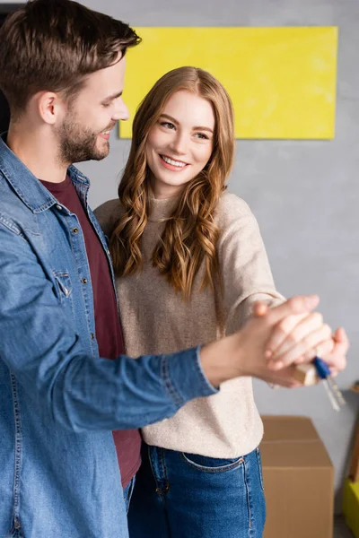 Zufriedenes Paar mit Händen und Schlüsseln zu Hause, bewegendes Konzept — Stockfoto