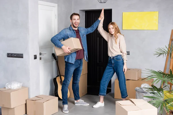 Aufgeregter Mann hält Karton in der Hand und gibt hoch fünf an zufriedene Frau, Umzugskonzept — Stockfoto