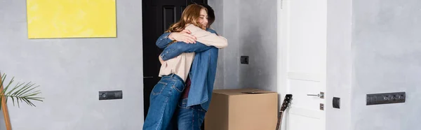 Imagem horizontal de casal alegre abraçando em nova casa — Fotografia de Stock