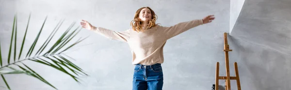 Cultivo panorámico de la mujer complacida con las manos extendidas saltando en el nuevo hogar, concepto de reubicación - foto de stock