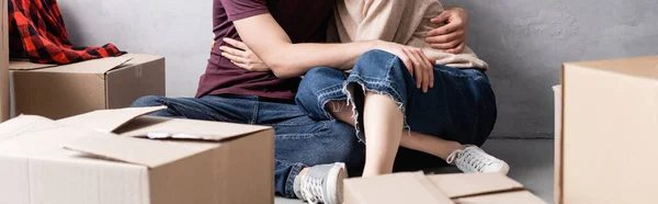 Colheita horizontal de homem sentado de chão e mulher abraçando perto de caixas — Fotografia de Stock