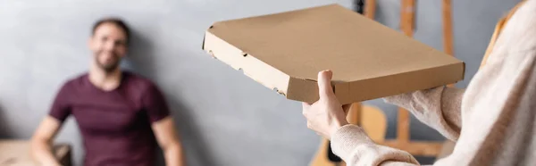 Foyer sélectif de la femme tenant boîte à pizza carton près du petit ami, culture panoramique — Photo de stock