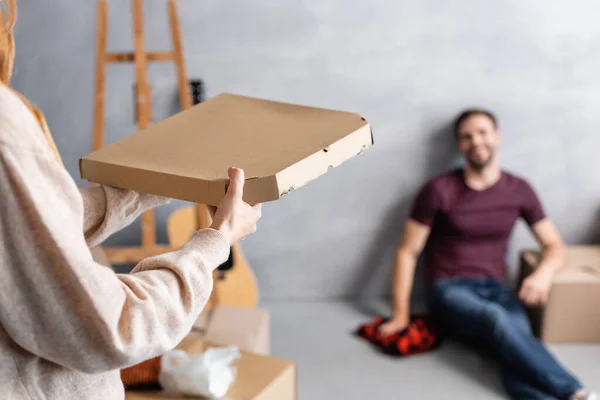 Enfoque selectivo de la mujer sosteniendo caja de pizza de cartón cerca de novio - foto de stock