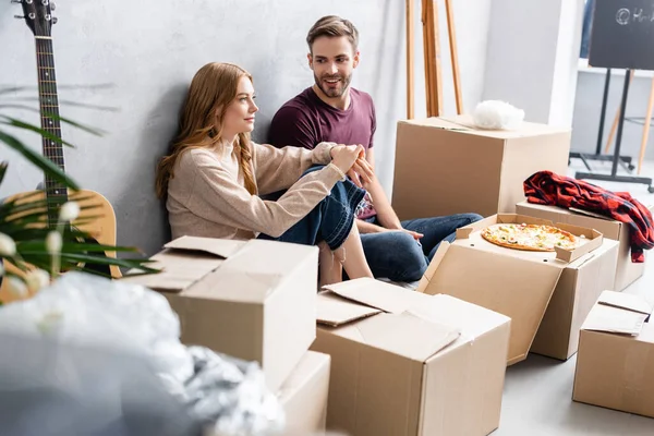 Selective focus of man looking at girlfriend near carton boxes and pizza, moving concept — Stock Photo