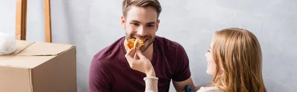 Panoramic concept of woman feeding boyfriend with tasty pizza — Stock Photo