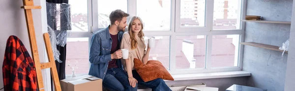 Website header of couple holding cups of tea near carton boxes, moving concept — Stock Photo