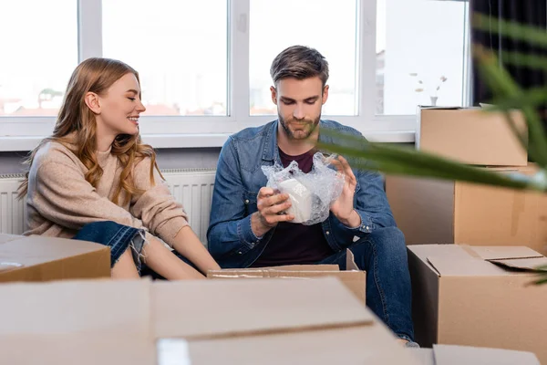 Enfoque selectivo del hombre sosteniendo taza envuelta cerca de novia y cajas, concepto en movimiento - foto de stock