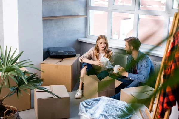 Selective focus of young woman unpacking box with man, moving concept — Stock Photo