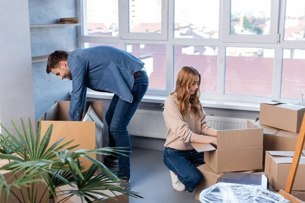 Uomo e donna disimballaggio scatole di cartone in nuova casa, concetto in movimento — Foto stock