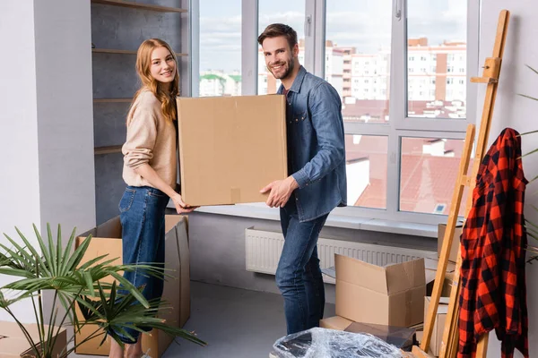 Man and woman holding carton box near plant, moving concept — Stock Photo