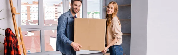 Panoramic shot of man and woman holding carton box, moving concept — Stock Photo