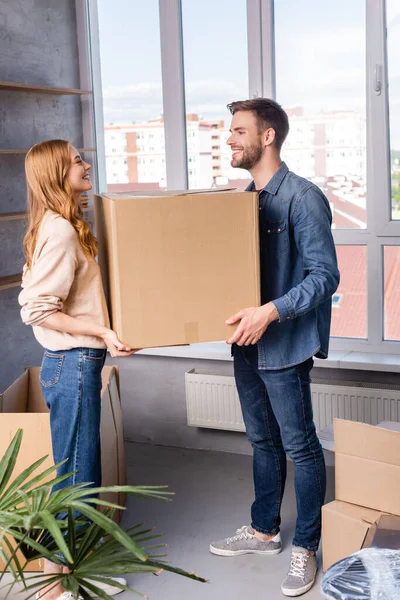 Joyful man and woman holding carton box, moving concept — Stock Photo