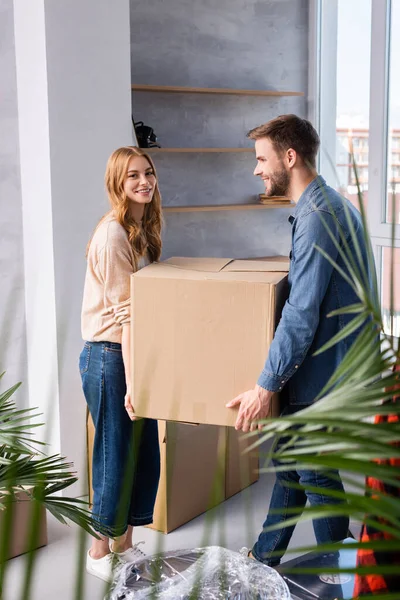 Enfoque selectivo de hombre y mujer alegre sosteniendo caja de cartón, concepto en movimiento - foto de stock