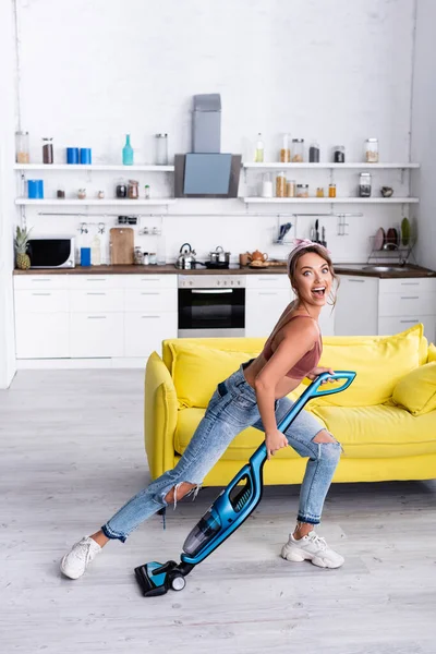 Excitada dona de casa se divertindo com aspirador de pó em casa — Fotografia de Stock