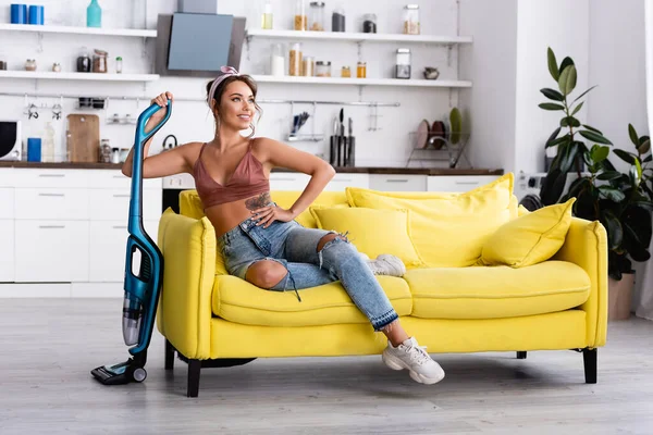 Housewife with hand on hip looking away and holding vacuum cleaner — Stock Photo