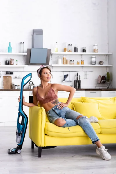 Housewife with hand on hip looking away and holding vacuum cleaner — Stock Photo